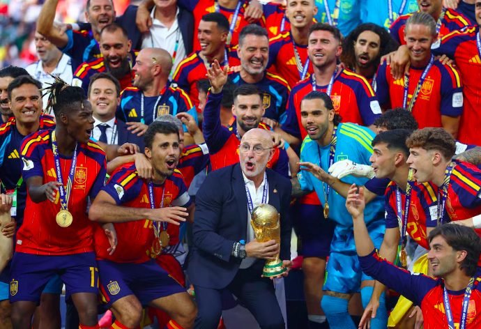 Spain coach Luis De La Fuente lifts the 2026 FIFA World Cup trophy alongside players.