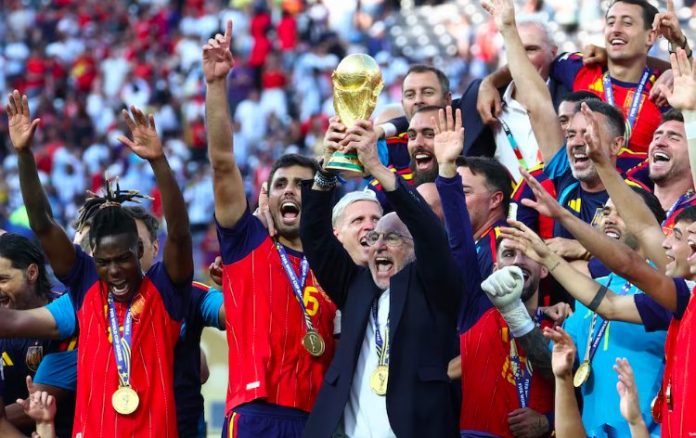 Spain coach Luis De La Fuente lifts the 2026 FIFA World Cup trophy alongside players.